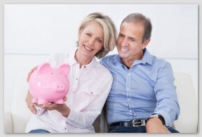 Happy Mature Couple Calculating Coin In The Piggybank